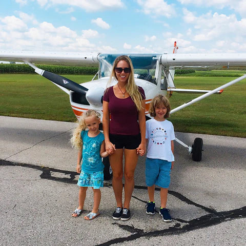 Kristy and two young children standing in front of a small plane