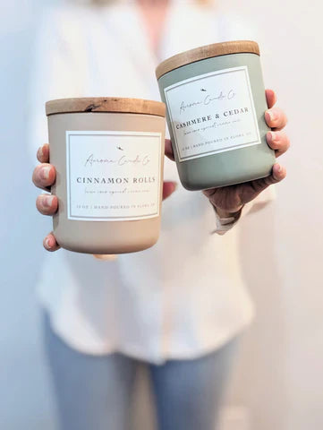 Hands holding up 2 candles with wooden lids
