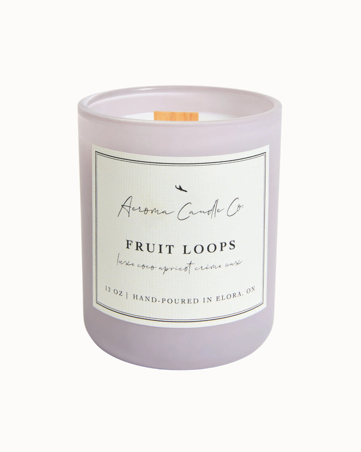 "Fruit Loops" candle in a light purple jar. There is a white square label on the candle stating the name of the business, scent, "luxe coco apricot crème wax", size, and "hand-poured in Elora, ON".