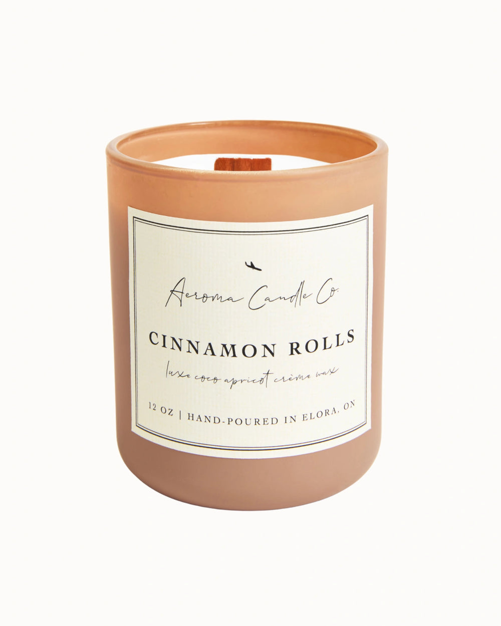 "Cinnamon Rolls" candle in a light beige jar. There is a white square label on the candle stating the name of the business, scent, "luxe coco apricot crème wax", size, and "hand-poured in Elora, ON".