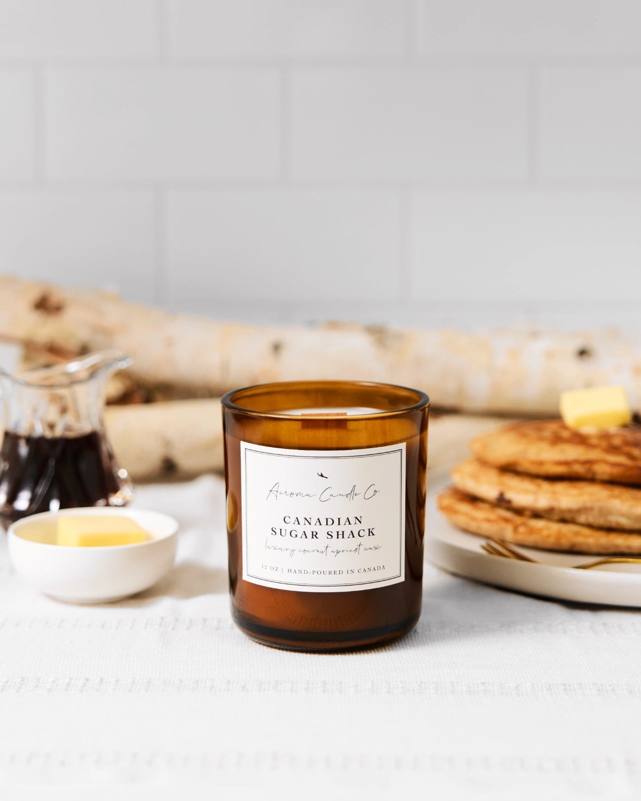 Candle labeled 'Canadian Sugar Shack' on a table with pancakes and syrup.