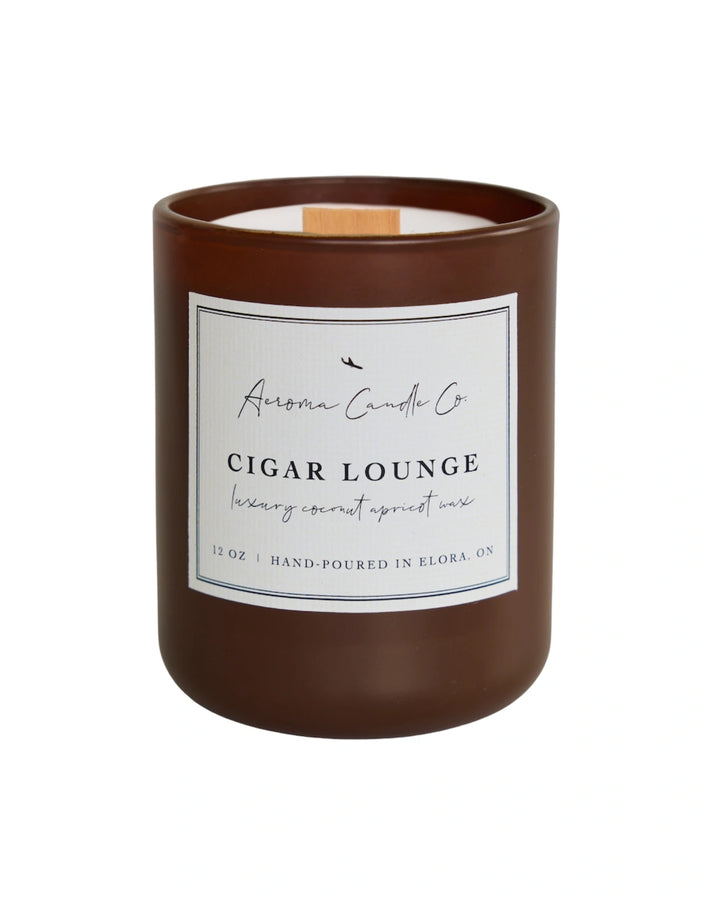 "Cigar Lounge" candle in a brown jar. There is a white square label on the candle stating the name of the business, scent, "luxe coco apricot crème wax", size, and "hand-poured in Elora, ON".