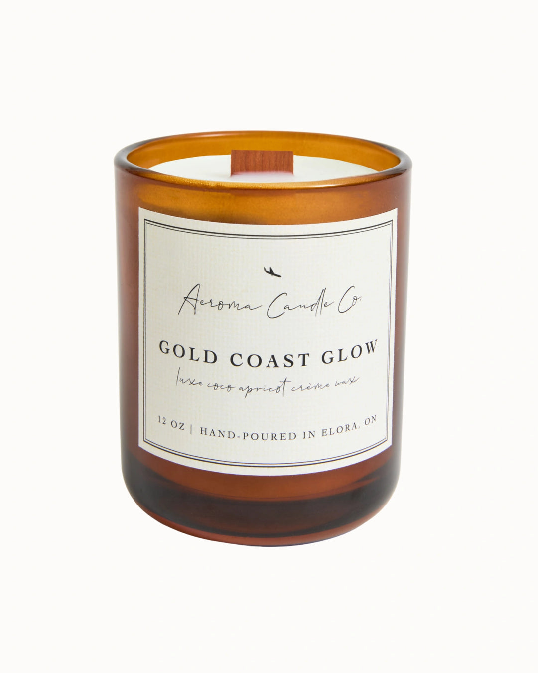 "Gold Coast Glow" candle in an opaque brown jar. There is a white square label on the candle stating the name of the business, scent, "luxe coco apricot crème wax", size, and "hand-poured in Elora, ON".