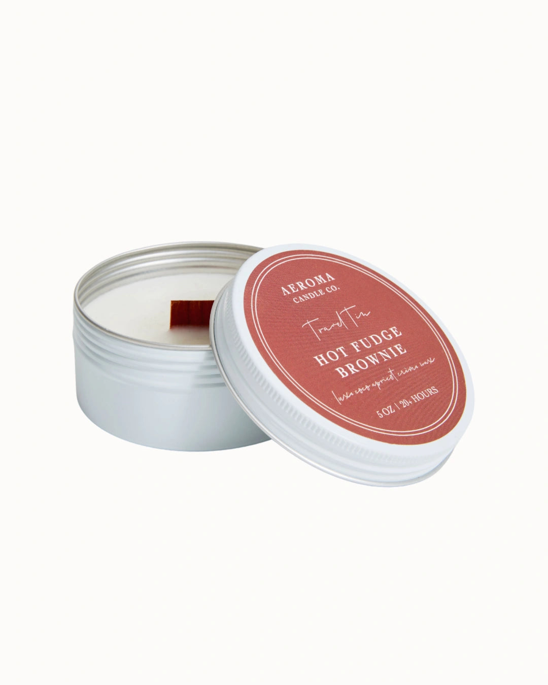 Candle in a tin with a dark red lid on a white background