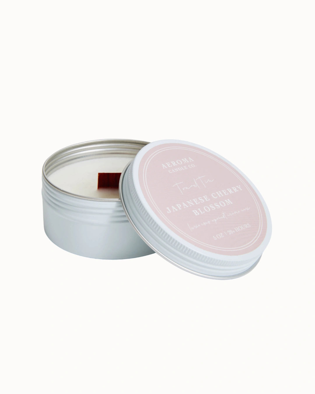 Candle in a tin with a light pink lid on a white background